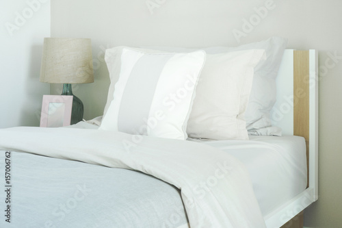 Close up pillows on bed with reading lamp and picture frame