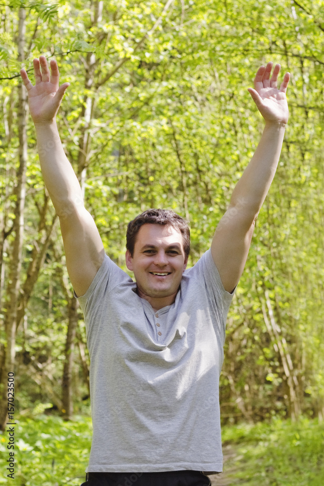 Happy joyful man is happy in the park and his hands up, victory, win, bright colored Happy joyful man is happy in the park and his hands up, victory, win, bright colored