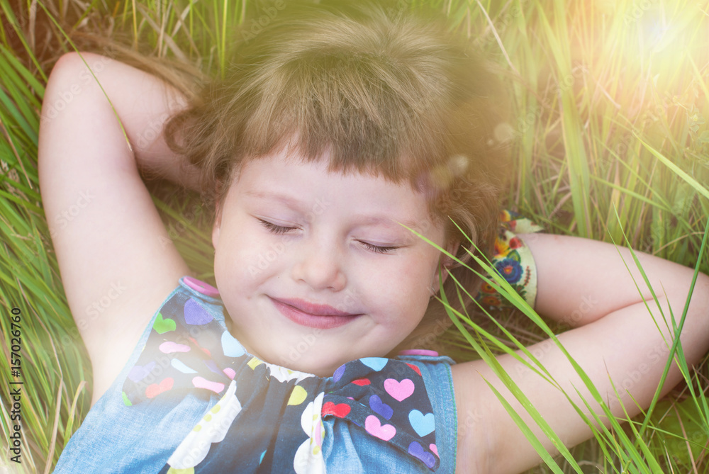 Happy Little Girl is enjoying in the Summer Park. Cute Child lying on the green grass. Healthy Kids - Happy Childhood Happy Little Girl is enjoying in the Summer Park. Cute Child lying on the green grass. Healthy Kids - Happy Childhood