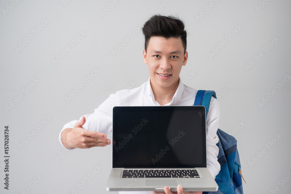 Young asian man in casual clothes holding and showing screen of laptop Young asian man in casual clothes holding and showing screen of laptop
