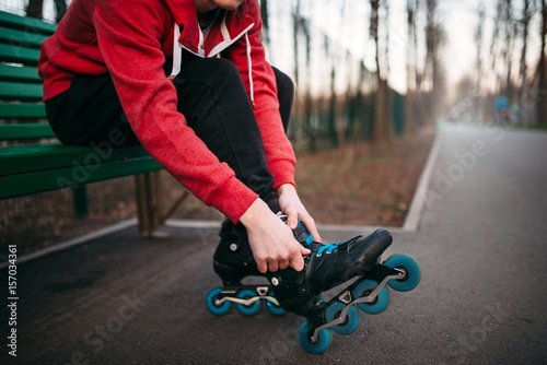 Roller skater sitting on bench and lace up skates