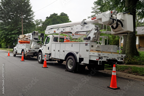 Rear and side view of parked communication utility trucks in residential neighborhood. Horizontal.