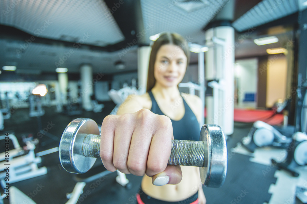Obraz premium The athletic woman hold a dumbbell in the gym. close up