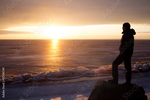 Man on rock on the sea in the ice - silhouette