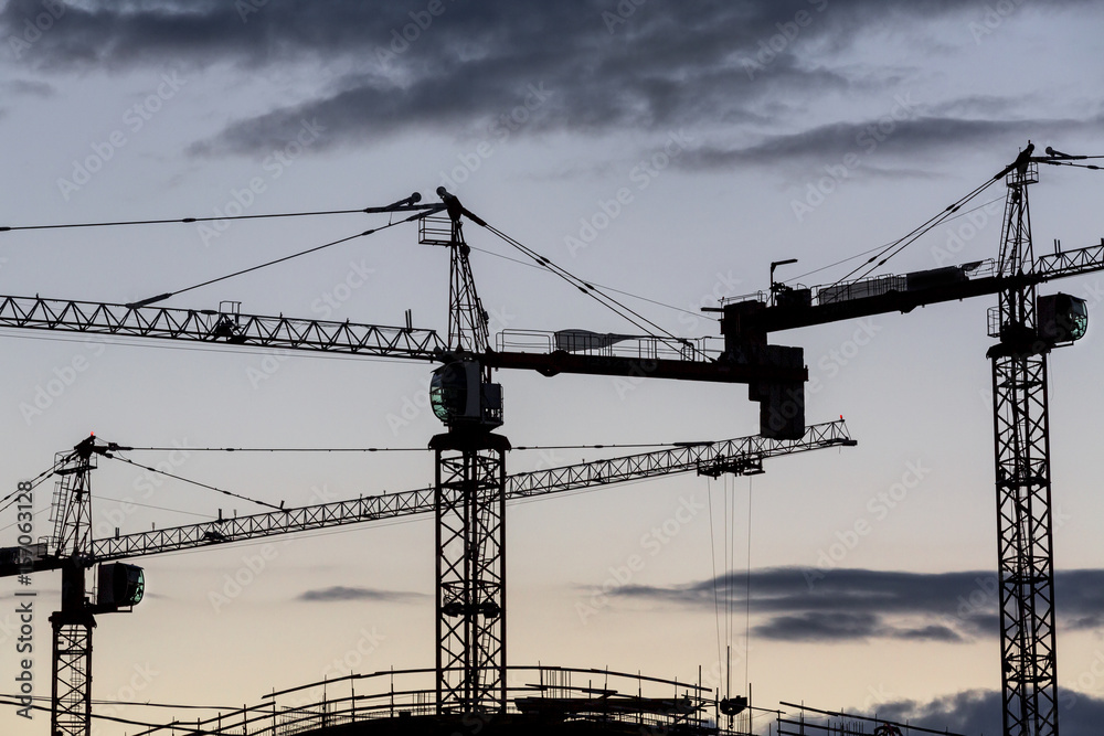 view of construction cranes on construction of an apartment house site with silhouetted over amazing abstract sunrise sky