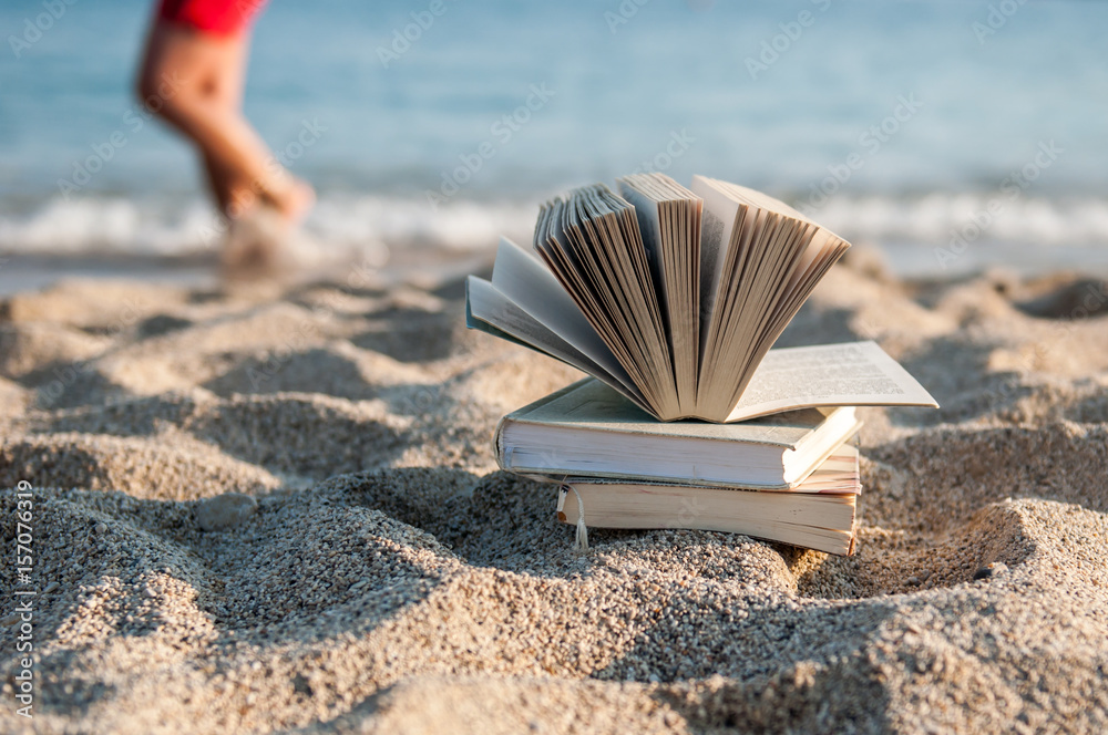 Open book at beach near the sea during bright sunny summer holiday vacation day Open book at beach near the sea during bright sunny summer holiday vacation day