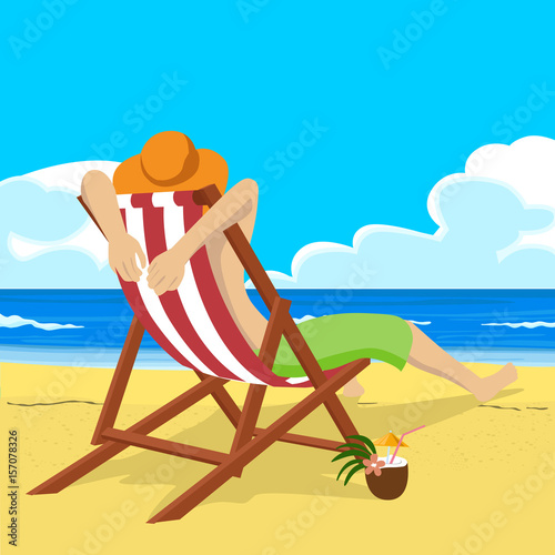 Young man in straw hat sitting in deck chair on tropical beach looks into the distance