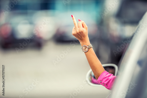 Attractive woman shows obscene gesture from a car.