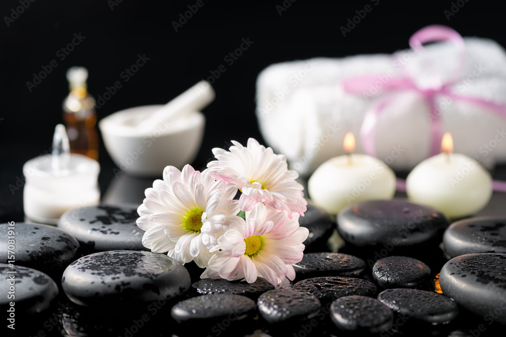 spa background of white daisy flowers, candles, fragrance oil, cosmetic cream, towels and zen basalt stones with water drops on black spa background of white daisy flowers, candles, fragrance oil, cosmetic cream, towels and zen basalt stones with water drops on black