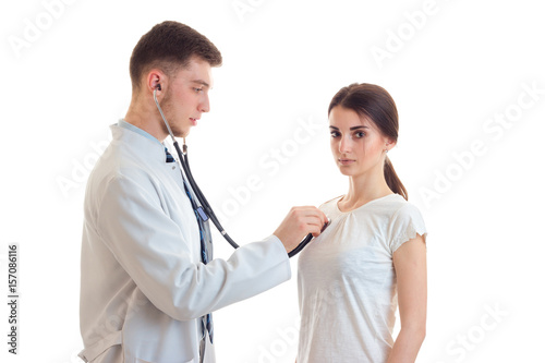 doctor in white robe at his patient's heart listens stethoscope close-up