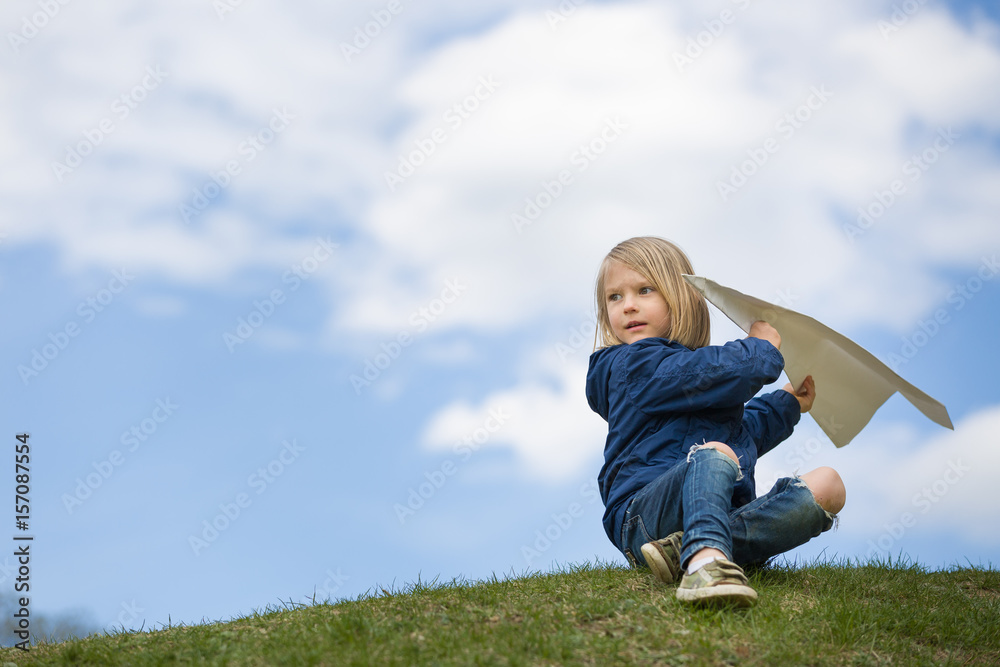 Cute kid boy launching paper airplane in the park. Small child having fun and playing with big handmade plane. Activities with children outdoors. Lifestyle