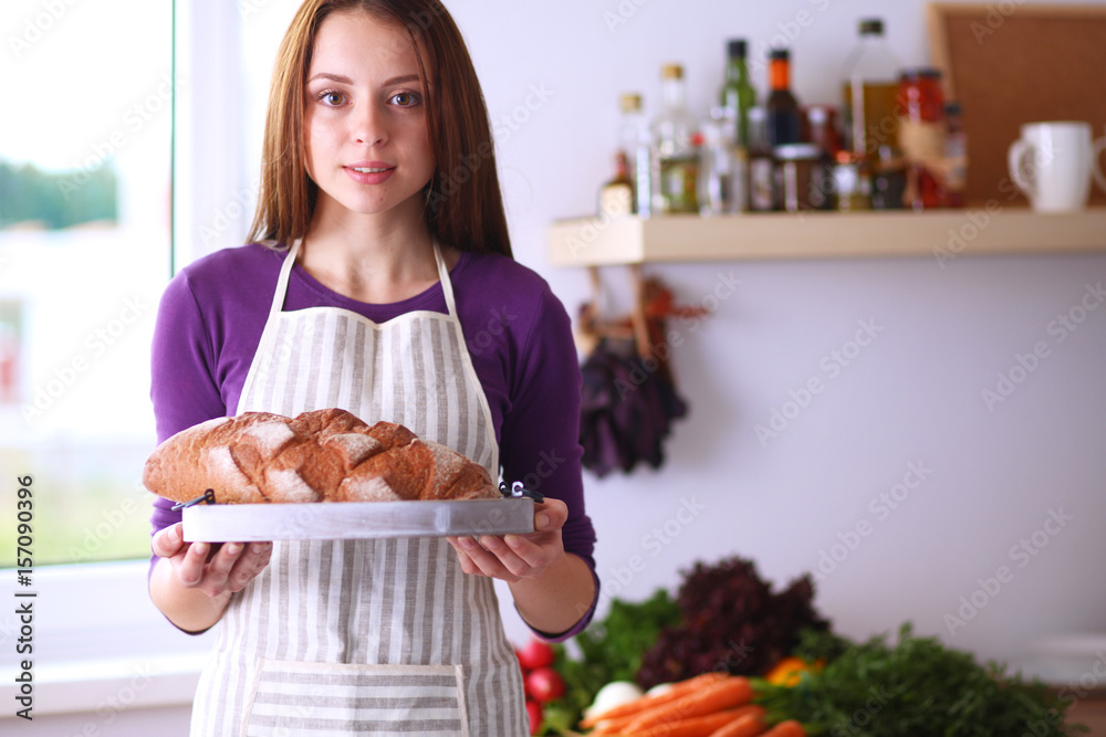 Young woman holding tasty fresh bread in her kitchen Young woman holding tasty fresh bread in her kitchen
