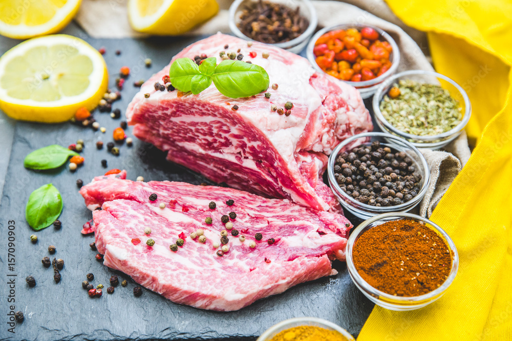 Fresh and raw meat. Still life of red meat steak ready to cook on the barbecue. Black slate background Fresh and raw meat. Still life of red meat steak ready to cook on the barbecue. Black slate background