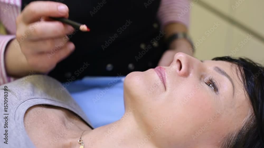 Cosmetician using pencil while doing a contour of client's lips Cosmetician using pencil while doing a contour of client's lips