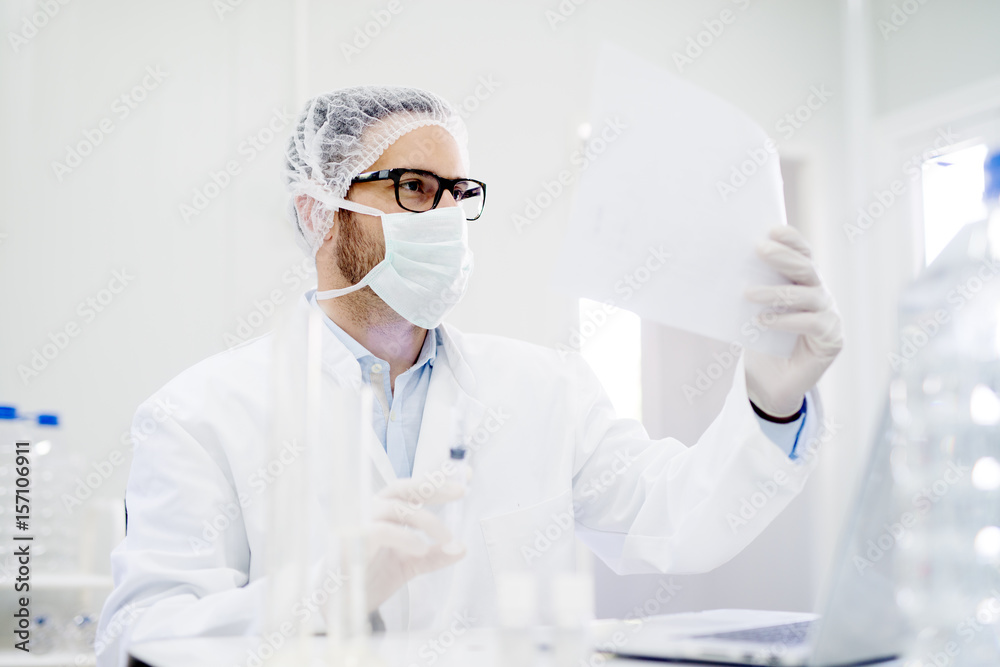 Lab technician doing water analysis, dressed in protective sterile equipment. Paper production. Lab technician doing water analysis, dressed in protective sterile equipment. Paper production.