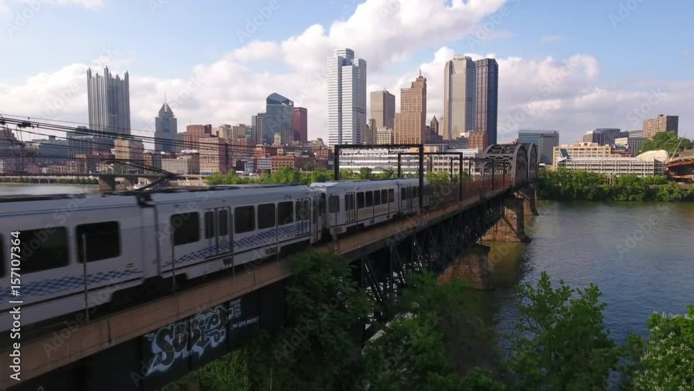 PITTSBURGH - Circa May, 2017 - A daytime aerial establishing shot of the early evening Pittsburgh skyline as a subway train travels in the foreground.	