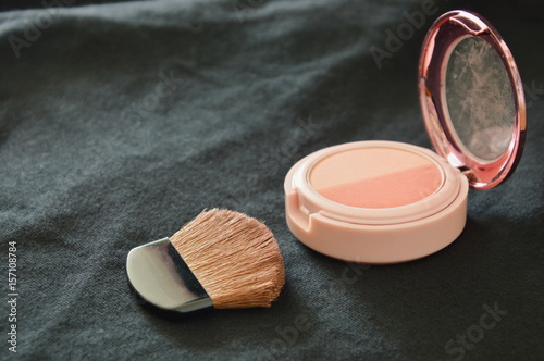 Фотография blusher powder cartridges and brush on black fabric background