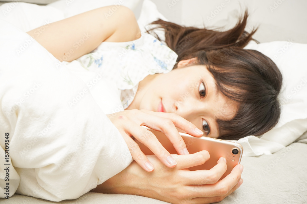 Young woman using a cellphone before sleeping Young woman using a cellphone before sleeping