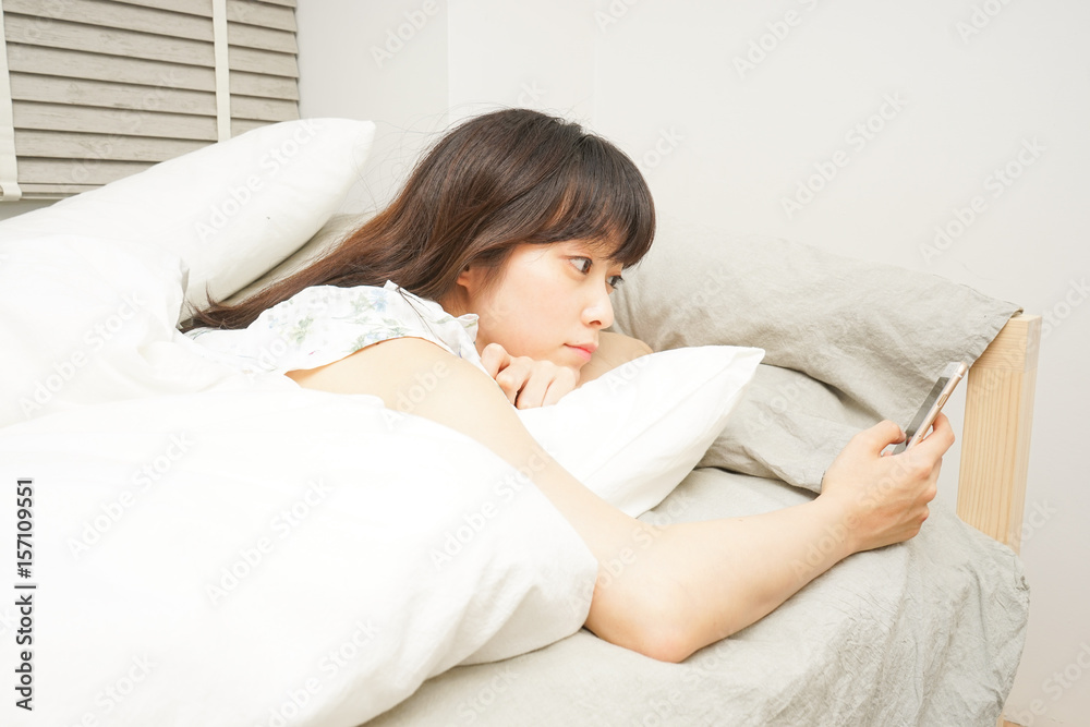 Young woman using a cellphone before sleeping Young woman using a cellphone before sleeping