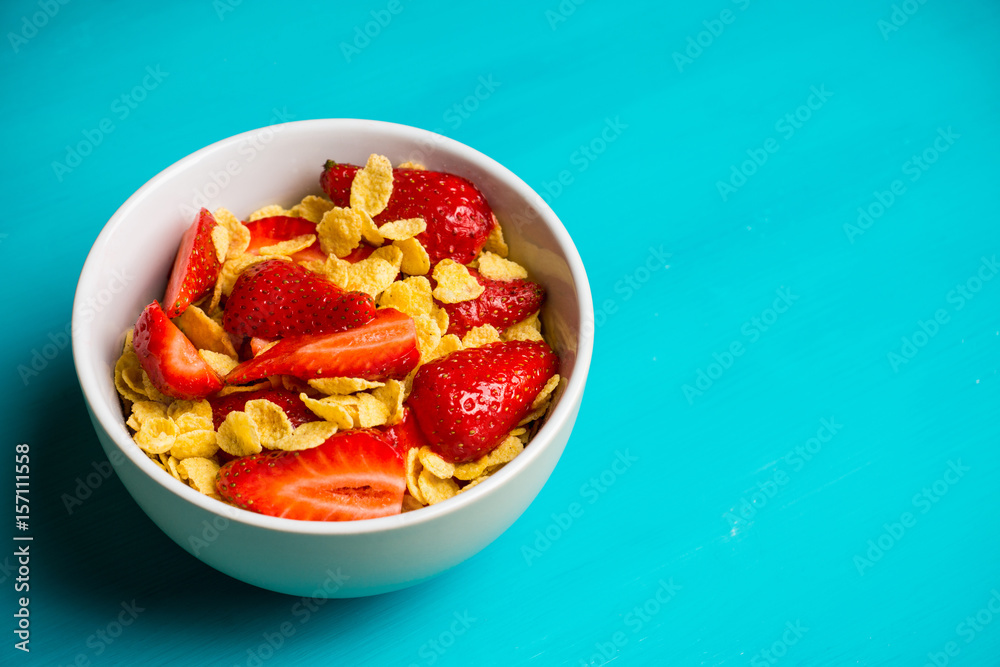 Corn flakes with fresh strawberry in bowl on the rustic background. Shallow depth of field. Corn flakes with fresh strawberry in bowl on the rustic background. Shallow depth of field.