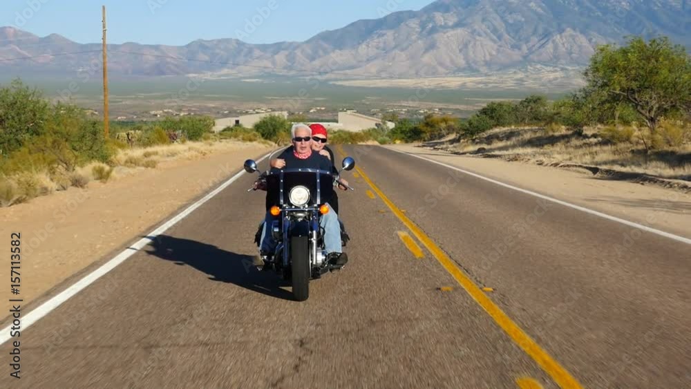 Mature couple riding on a motorcycle on a scenic road Mature couple riding on a motorcycle on a scenic road