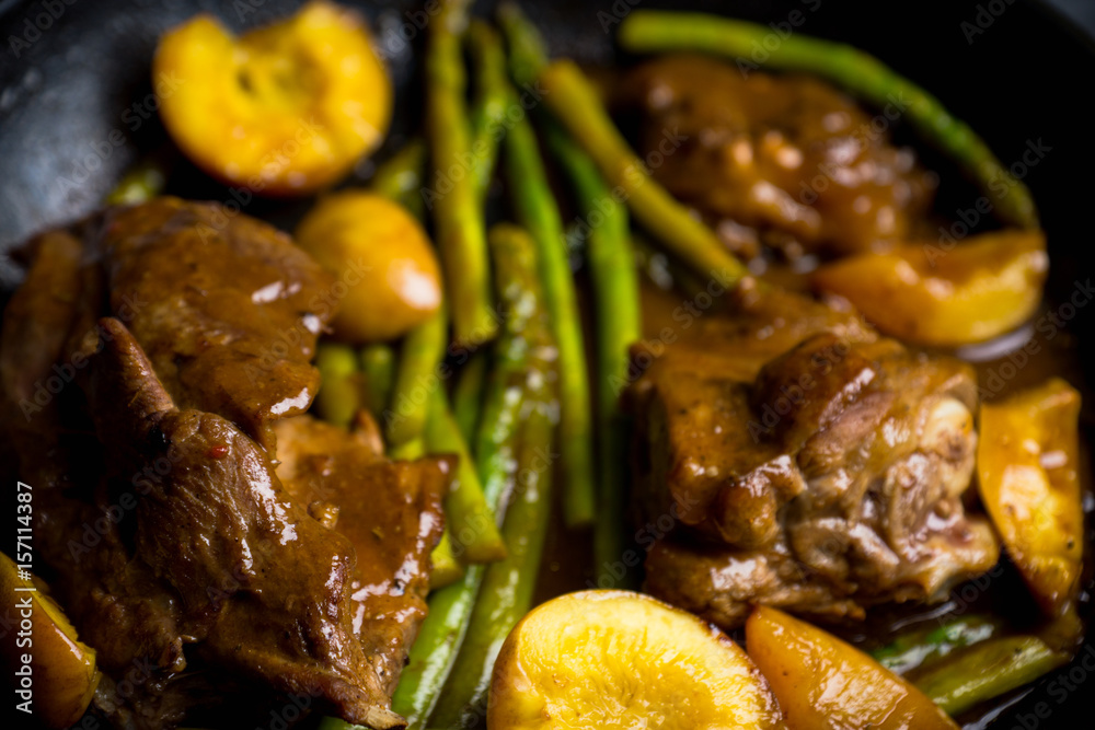 Grilled pork with asparagus and peaches in pan on the black background. Shallow depth of field. Grilled pork with asparagus and peaches in pan on the black background. Shallow depth of field.