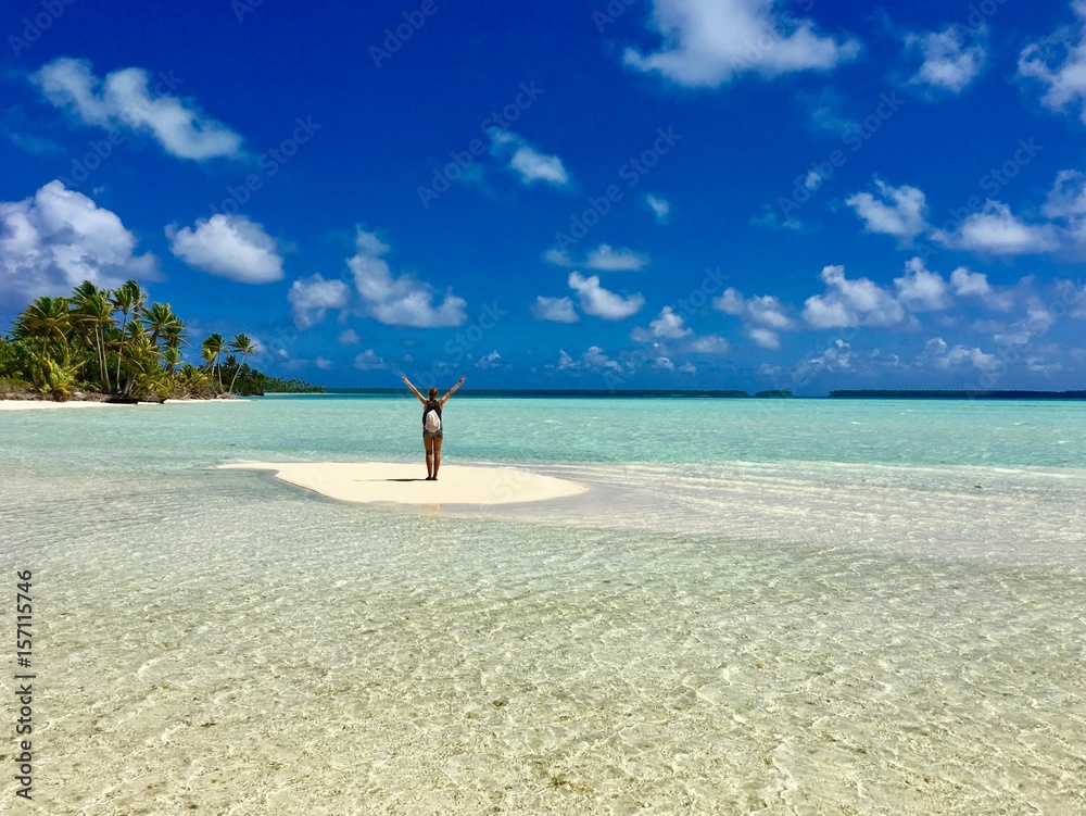 Beautiful young lady standing on a small sandbank in the turquoise lagoon of Marlon Brando's atoll Tetiaroa, Tahiti, French Polynesia