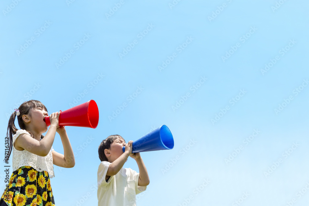 土手でメガホンで叫ぶ2人の子供