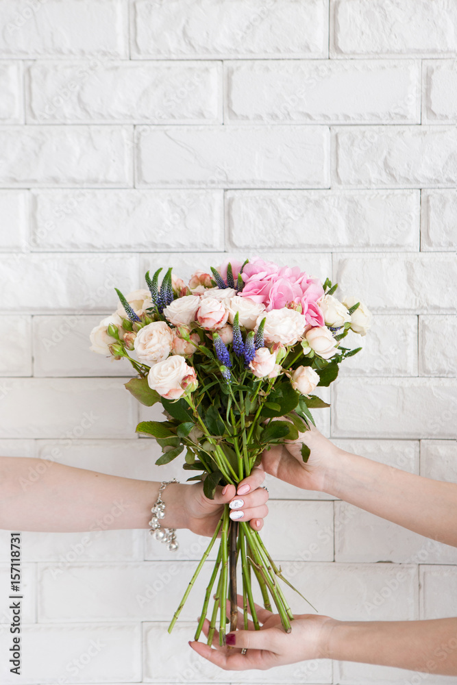 Obraz premium Delivery of a floral workshop. The customer receives his order-a bouquet of pink roses and wild flower. Hand courier pass flowers to the buyer