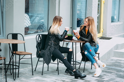 Two beautiful young women drinking coffee and gossiping in nice restaurant outdoor . The weather is great and sunny for walking rest relaxing spending time with best friends 