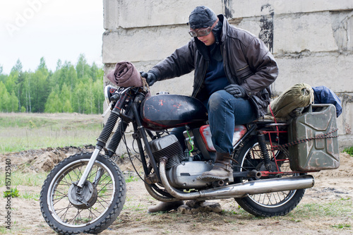 A post apocalyptic man on motorcycle near the destroyed building