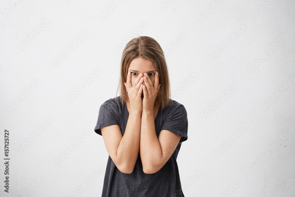 Stressed scared female student in casual t-shirt covering her face ...