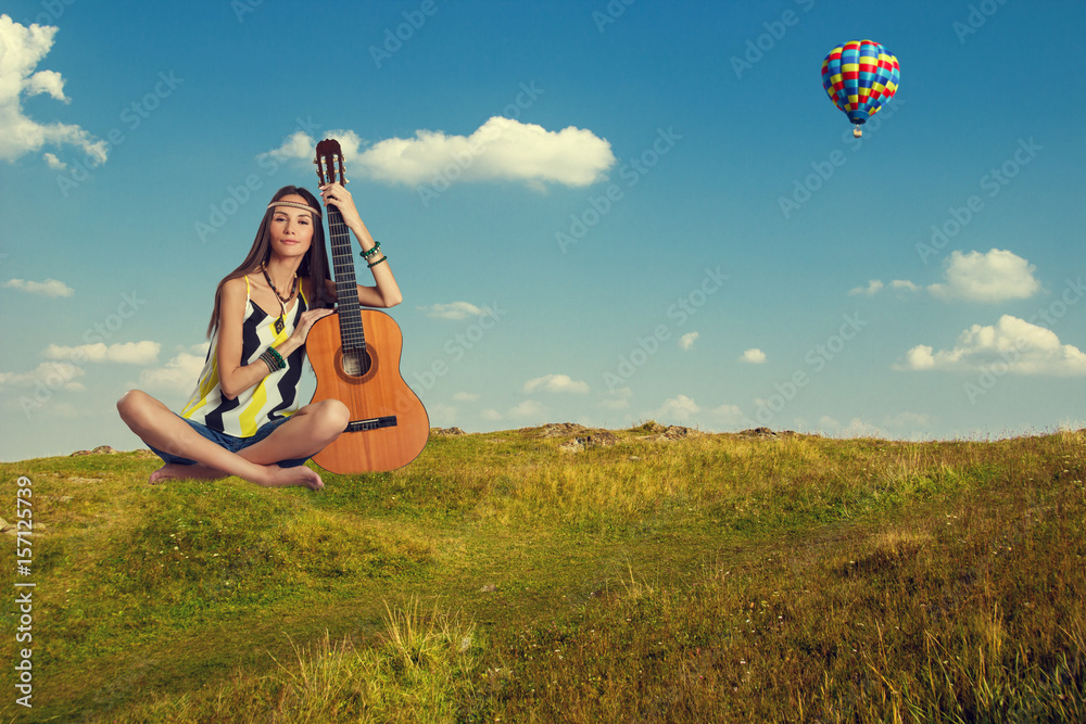 Young hippie woman sitting with a guitar outdoors. Young hippie woman sitting with a guitar outdoors.
