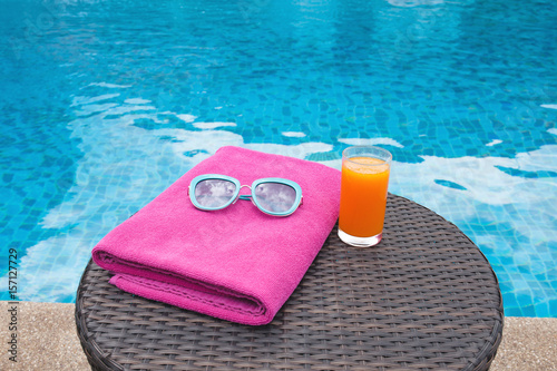 Summertime orange juice hat and sunglasses relax near swimming pool