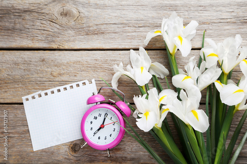 Fototapeta Naklejka Na Ścianę i Meble -  Bouquet of iris flowers with alarm clock on grey wooden table