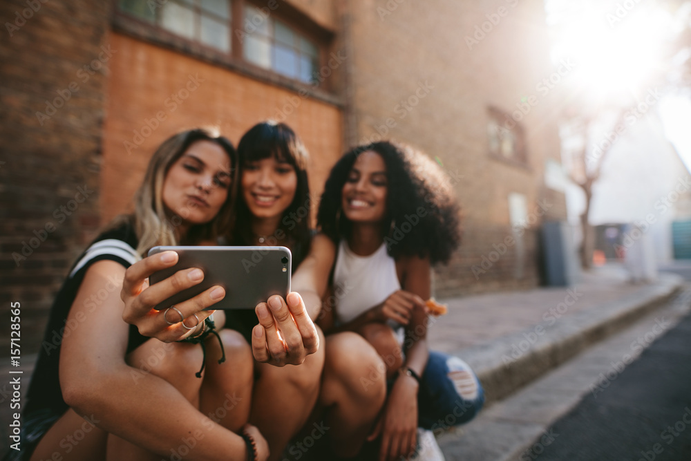 Three smiling female friends making selfie