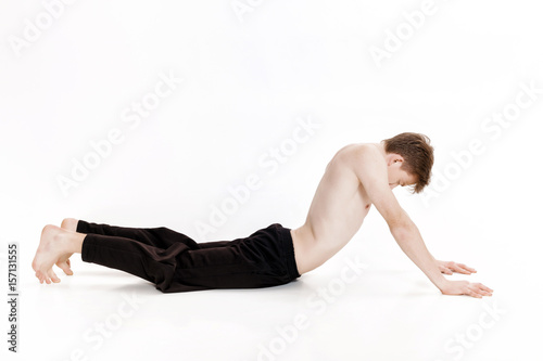 Young man doing yoga exercises. Studio shot on white background