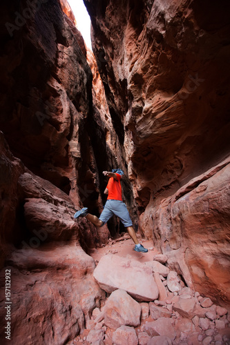 A man jumps from stone in Jenny's canyon within Snow canyon State Park in Utah, USA