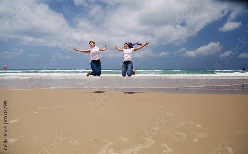 Outdoor portrait of two women jumping on the beach