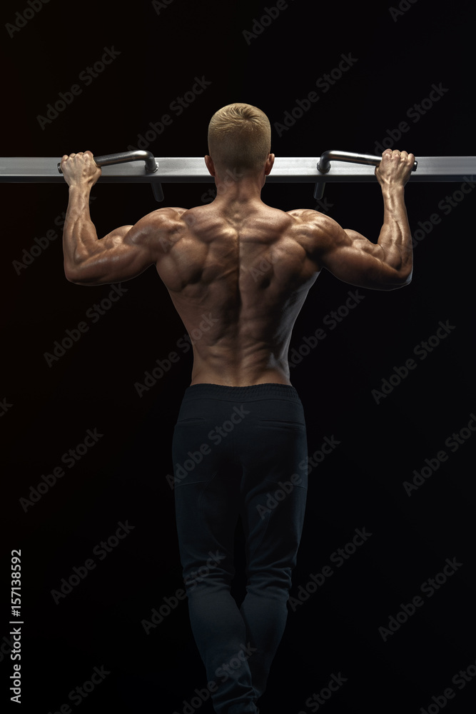 Power muscular bodybuilder guy doing pullups in gym. Fitness man pumping up lats muscles. Fitness and bodybuilding training health lifestyle concept