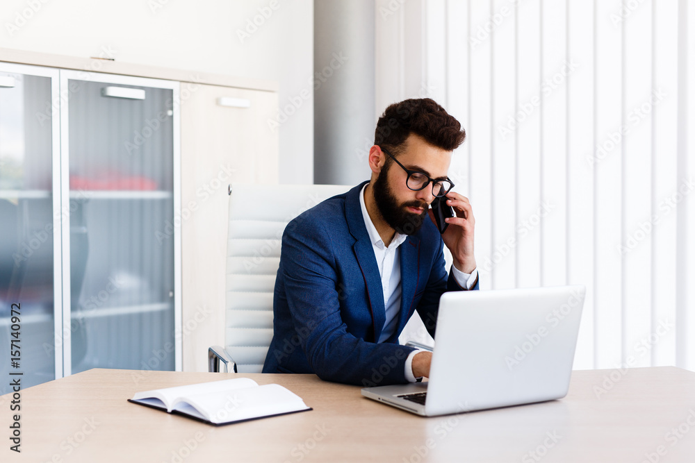 Businessman on his work place using laptop and phone to communicate with others Businessman on his work place using laptop and phone to communicate with others