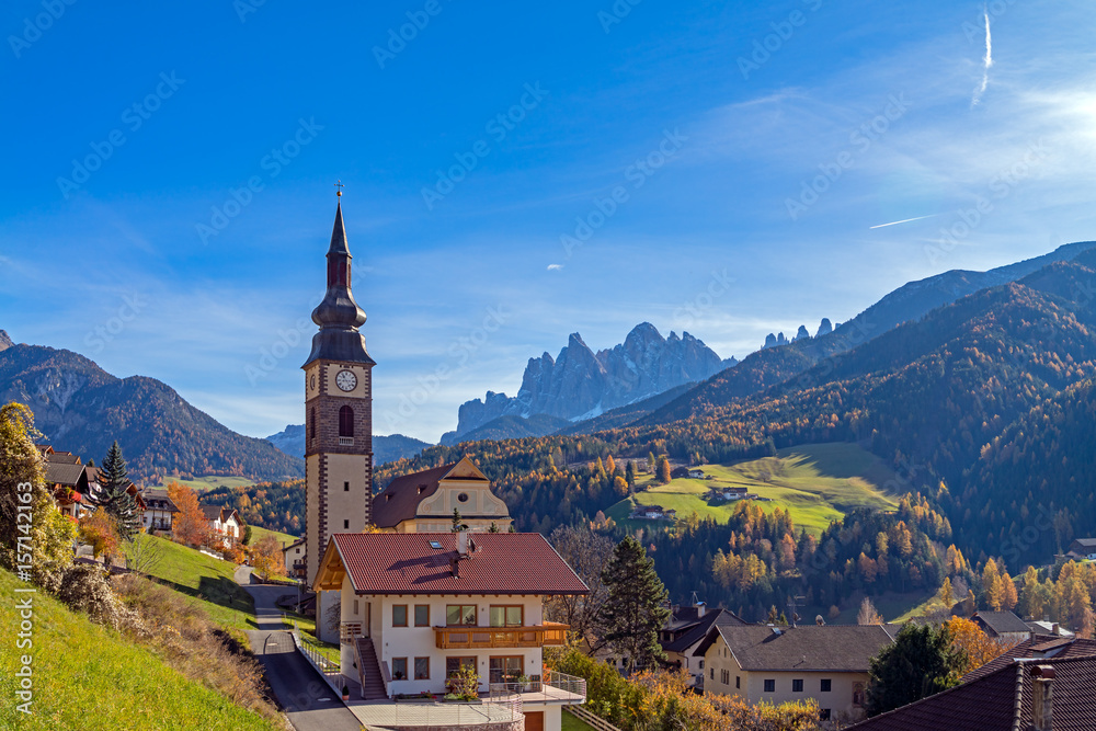 Italy. Dolomites. Autumn landscape with bright colors, house and larch trees in the sunlight.
