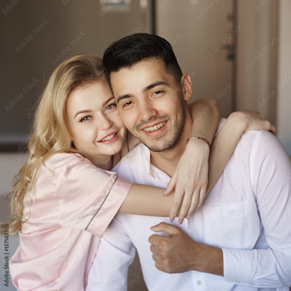 Young romantic couple at home. Caucasian blonde woman and brunette man. Lovers hugging in living room. Young romantic couple at home. Caucasian blonde woman and brunette man. Lovers hugging in living room.