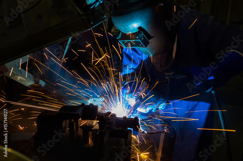 Industrial worker is welding metal in factory