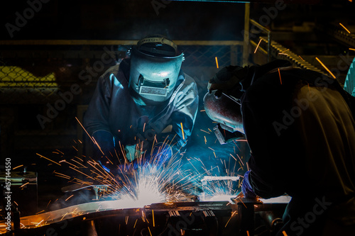 Team workers are welding part in factory
