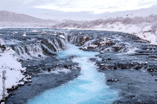 Bruarfoss waterfall in Winter cover with snow blue water from glacier. Iceland