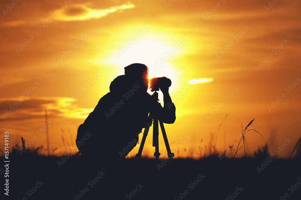 Silhouette of photographer with camera and tripod