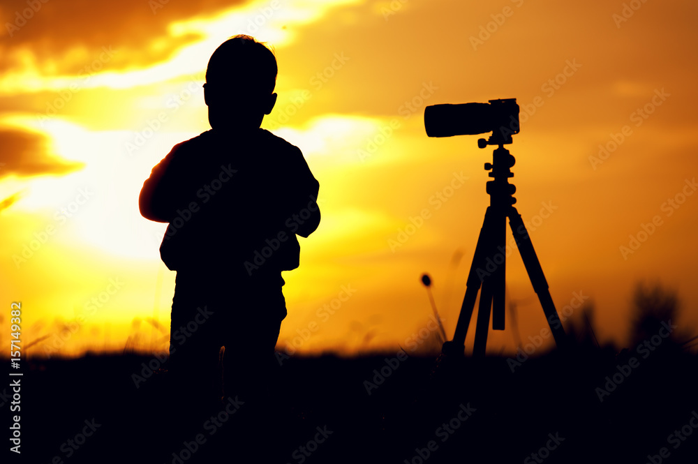 Silhouette picture of boy standing with camera
