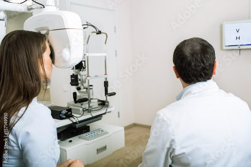 patient woman having her eyes examined by an optometrist using phoropter  in ophthalmology clinic.