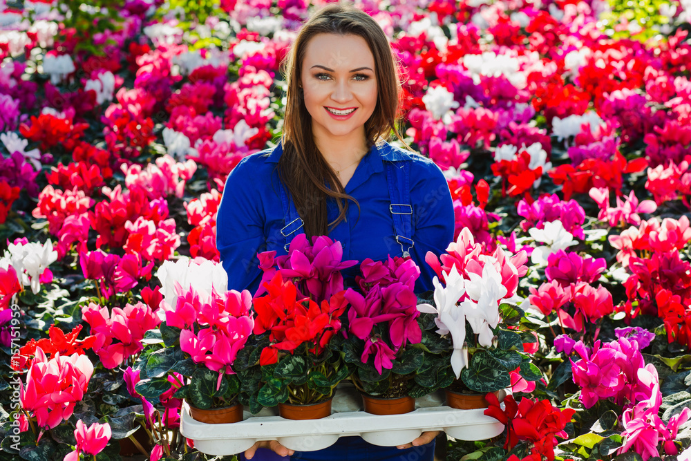 Smiling gardener florist holding potted flowers
